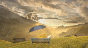 Two teddies sit on a bench viewing a valley. The bears are under an umbrella. Its raining, but there is sunlight within the valley, tinting the image with hope.